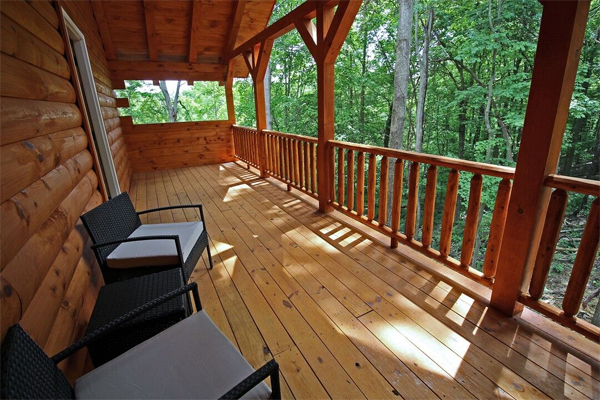 wooded area, long wrap around porch, 2 chairs on deck