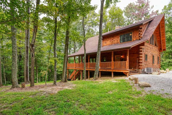 log cabin in woods with gravel driveway