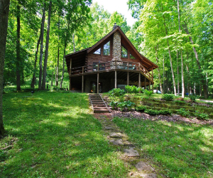 cabin on hill with two story and upstairs deck overlooking the wooded area