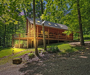 cabin on hill with two story and upstairs deck overlooking the wooded area