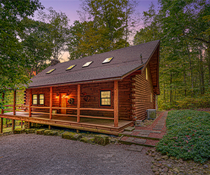 cabin on hill with two story and upstairs deck overlooking the wooded area