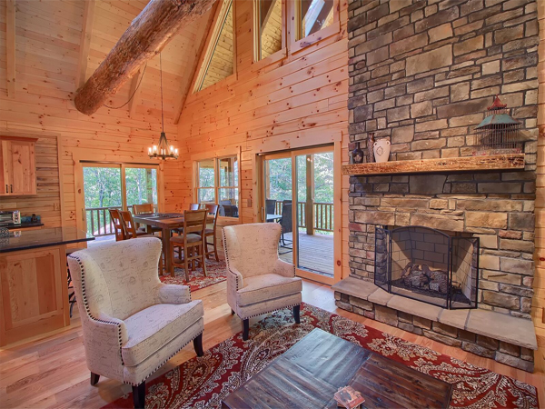 stone fireplace, cloth high back armchairs, windows to outside area