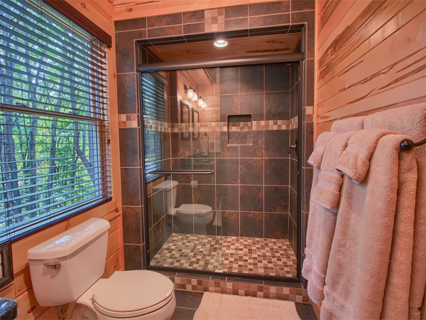 tiled shower with glass door, towel rack, toilet
