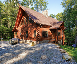huge lodge with two story view of window of room on top and total wrap around deck and covered deck on the side