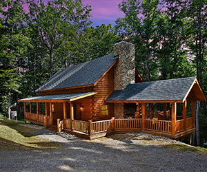 log cabin set back from road with wrap around porch and a green roof with stone fireplace