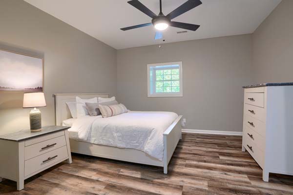 A bedroom with a ceiling fan and a bed