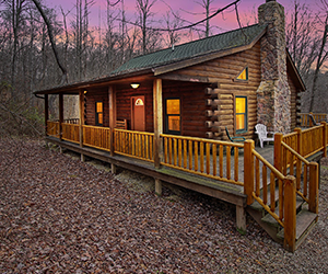 side view of log cabin with wrap around deck and side view of stone fireplace