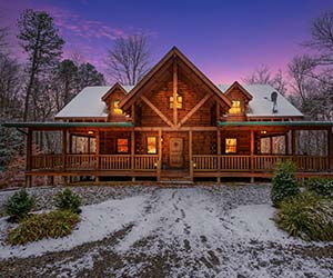 huge lodge with two story view of window of room on top and total wrap around deck and covered deck on the side