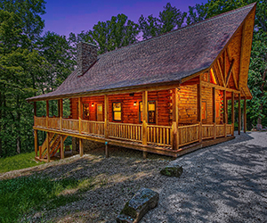 twilight picture of lodge with open porch and wrap around deck