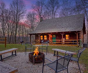 log cabin with long front porch with fence